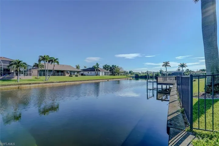 View of dock with a lawn and a water view