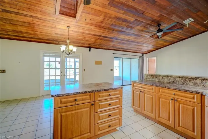 Kitchen with wood ceiling, decorative light fixtures, light tile patterned floors, and a healthy amount of sunlight