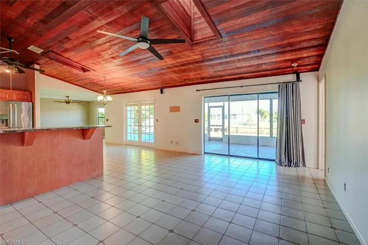 Unfurnished living room with light tile patterned flooring, ceiling fan, wooden ceiling, vaulted ceiling, and french doors