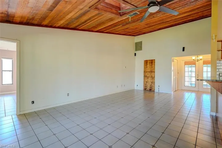 Spare room with ceiling fan with notable chandelier, wooden ceiling, and a wealth of natural light