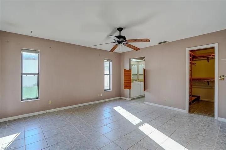 Unfurnished bedroom with a spacious closet, multiple windows, and ensuite bath