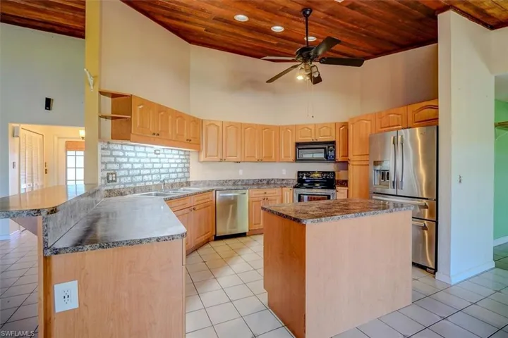 Kitchen with high vaulted ceiling, a center island, and stainless steel appliances