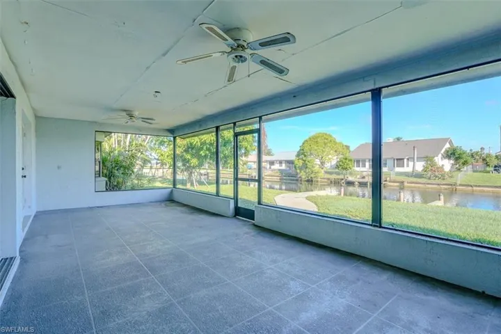 Unfurnished sunroom featuring ceiling fan and a water view