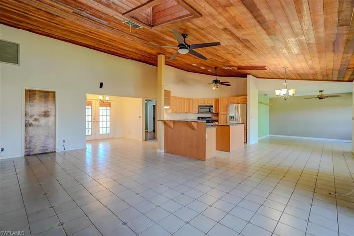 Kitchen with stainless steel appliances, light tile patterned floors, high vaulted ceiling, and wooden ceiling