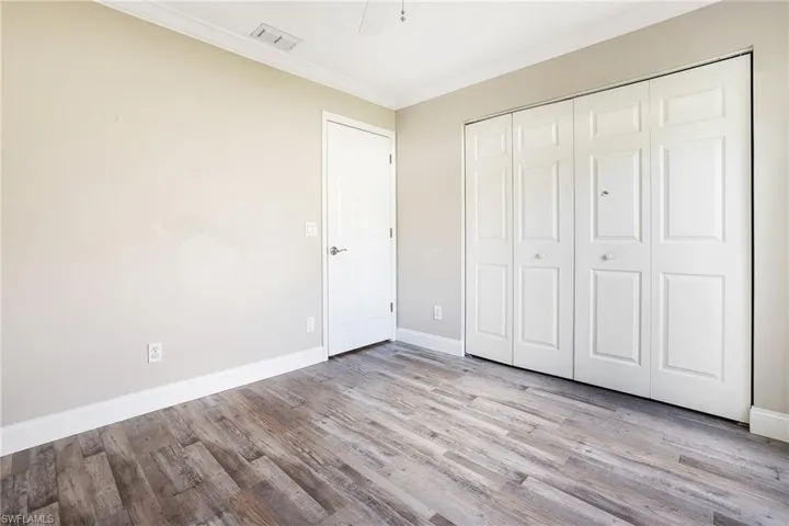 Unfurnished bedroom with ornamental molding, a closet, ceiling fan, and light hardwood / wood-style floors