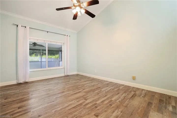 Empty room featuring light wood-type flooring, ceiling fan, lofted ceiling, and ornamental molding