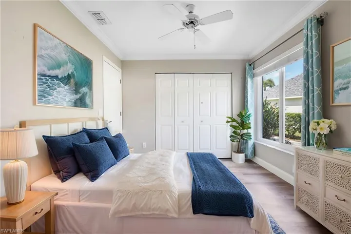 Bedroom with crown molding, light hardwood / wood-style floors, ceiling fan, and a closet