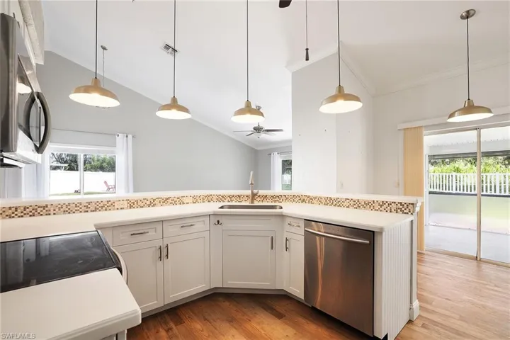 Kitchen with decorative light fixtures, stainless steel appliances, sink, ceiling fan, and light hardwood / wood-style floors