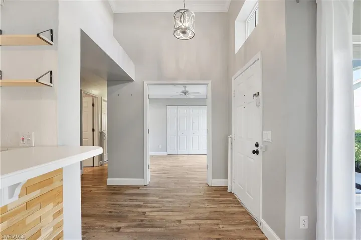 Entrance foyer featuring a wealth of natural light, crown molding, ceiling fan with notable chandelier, and hardwood / wood-style flooring