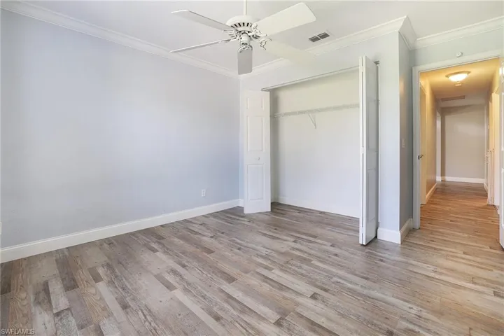 bedroom with crown molding, ceiling fan, a closet, and light wood-type flooring