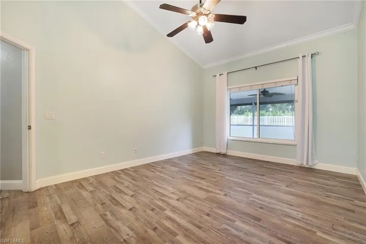 Spare room featuring ceiling fan, ornamental molding, light hardwood / wood-style floors, and vaulted ceiling