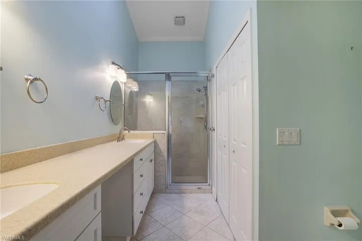 Bathroom featuring tile patterned flooring, an enclosed shower, crown molding, and vanity