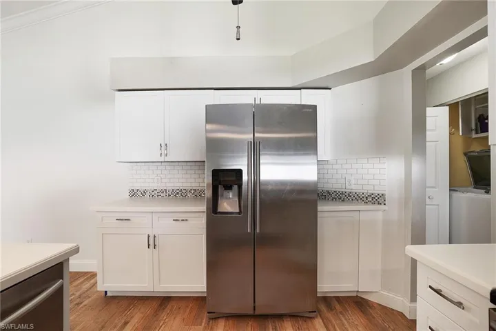 Kitchen featuring stainless steel fridge with ice dispenser, hardwood / wood-style flooring, backsplash, and white cabinets