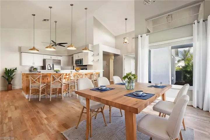 Dining room with crown molding, light hardwood / wood-style floors, and high vaulted ceiling