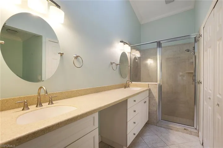 Bathroom featuring crown molding, vanity, walk in shower, and tile patterned flooring