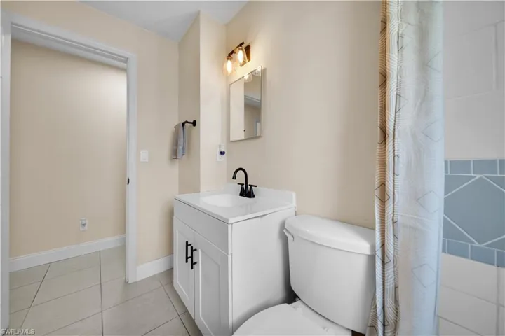 Full bathroom with baseboards, toilet, tile patterned flooring, and vanity