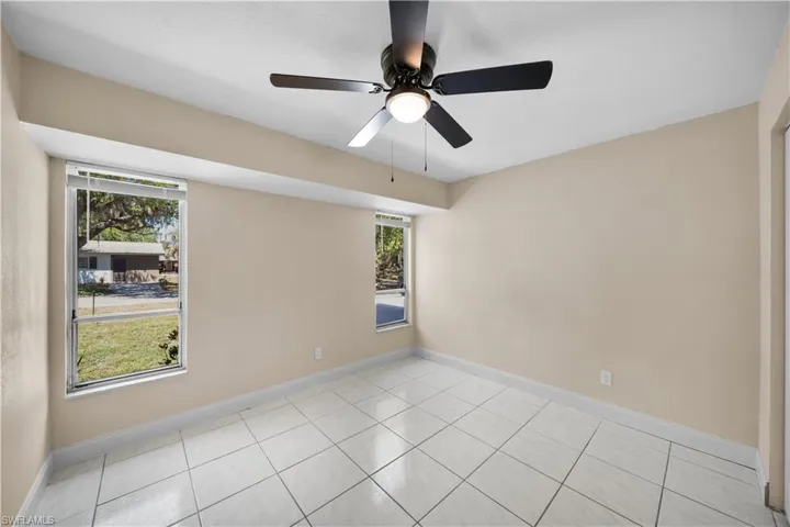 Empty room featuring baseboards, ceiling fan, light tile patterned flooring, and plenty of natural light