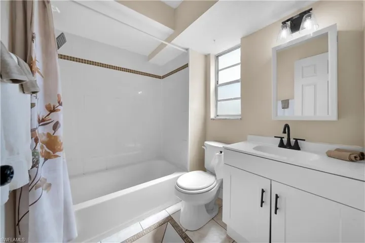 Full bath with tile patterned floors, toilet, vanity, and shower / bathtub combination with curtain
