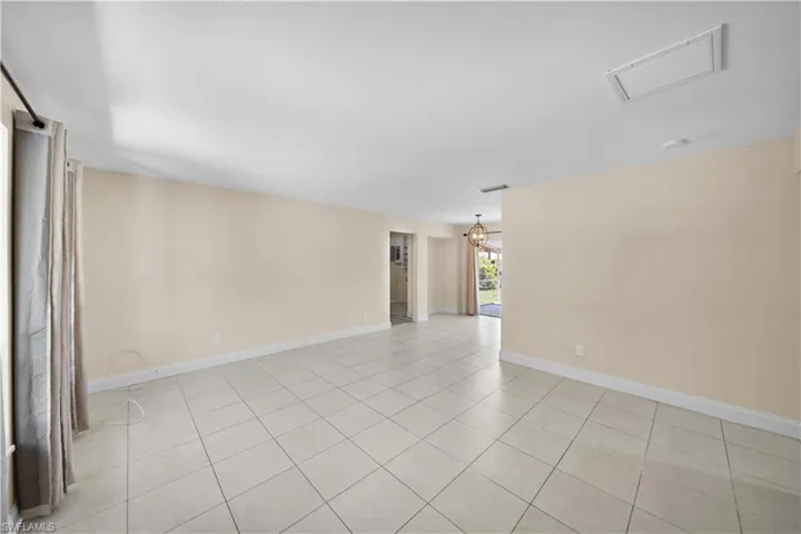 Unfurnished room featuring light tile patterned floors, a notable chandelier, baseboards, and visible vents