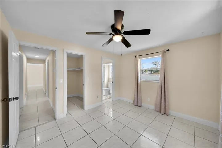 Unfurnished bedroom featuring light tile patterned flooring, a spacious closet, baseboards, and a closet