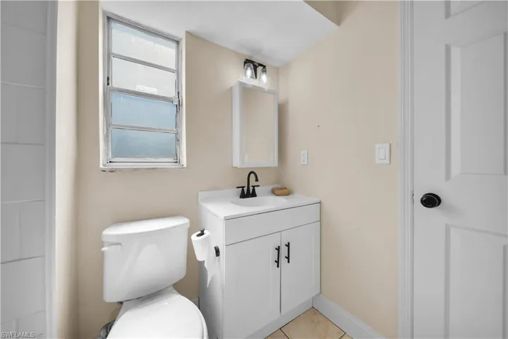 Bathroom with toilet, vanity, tile patterned floors, and baseboards