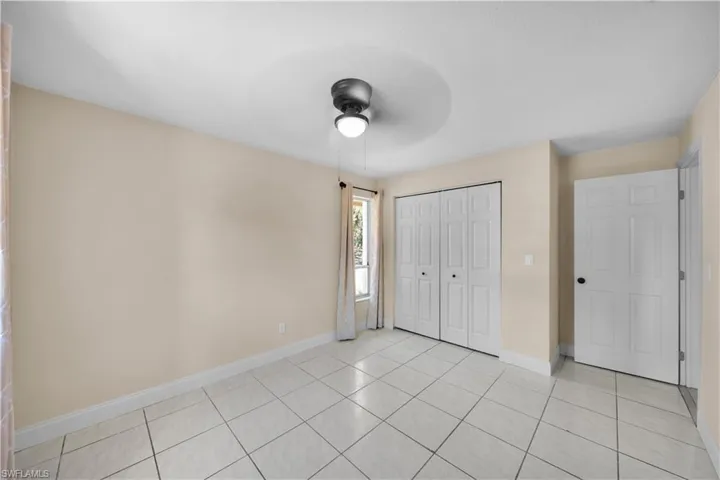Unfurnished bedroom featuring baseboards, a closet, ceiling fan, and light tile patterned floors