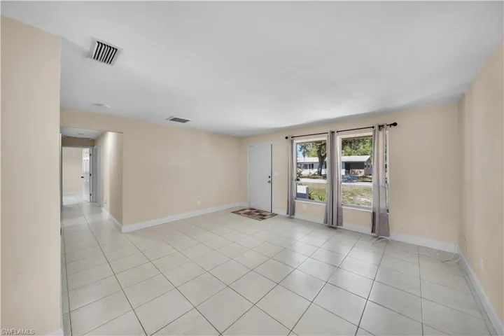 Empty room with light tile patterned floors, baseboards, and visible vents