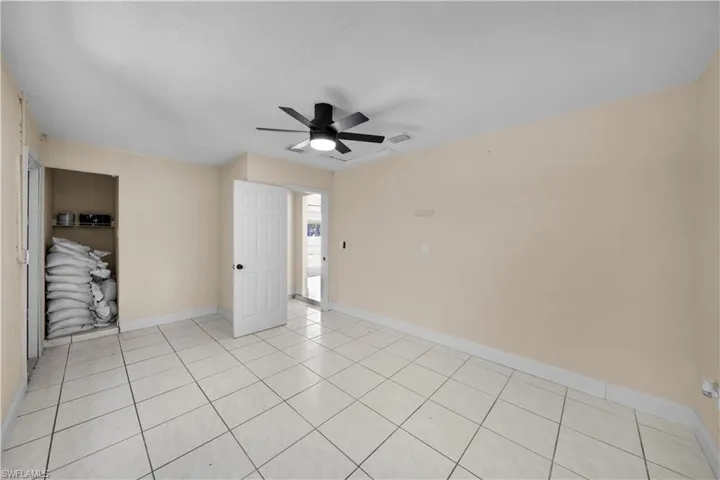 Unfurnished bedroom with light tile patterned flooring, baseboards, visible vents, and a ceiling fan