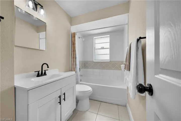 Full bath featuring toilet, vanity, shower / bath combo, tile patterned flooring, and baseboards