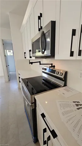 Kitchen with appliances with stainless steel finishes, white cabinetry, and light countertops