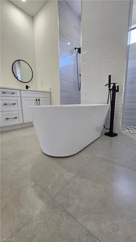 Bathroom with a soaking tub, vanity, tile walls, and a shower