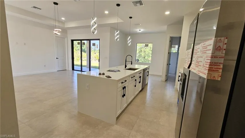 Kitchen featuring stainless steel appliances, white cabinets, pendant lighting, recessed lighting, and light countertops