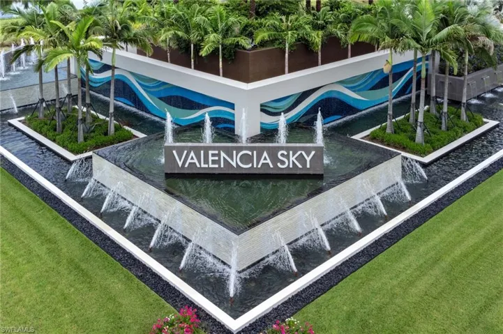 Contemporary water feature with multiple fountains and a central sign, complemented by a vibrant blue and white wave-patterned wall mural