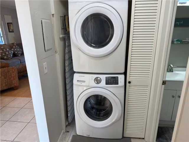 Laundry area featuring stacked washing machine and dryer and light tile patterned floors