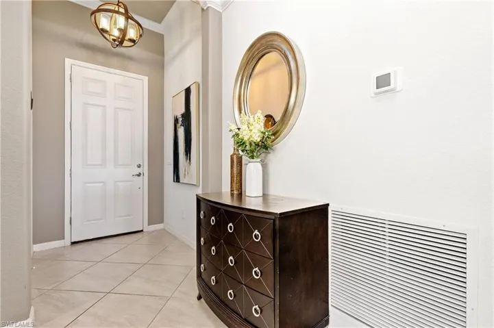 Foyer with light tile patterned floors, crown molding, and a chandelier