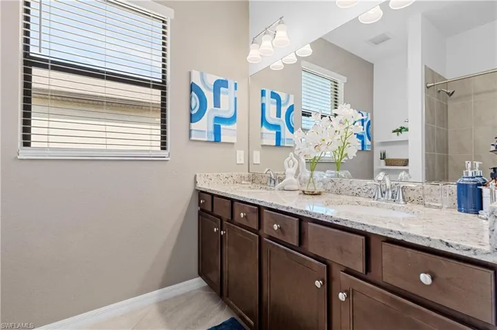 Guest Full bath serving bedroom 2 & 3 featuring double vanity, light tile patterned floors, and a shower