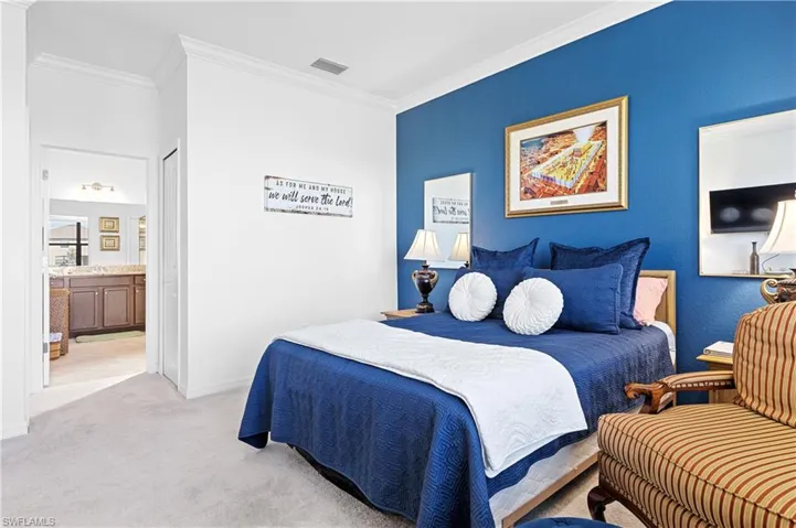 Bedroom featuring ornamental molding, light colored carpet, ensuite bath, and a closet
