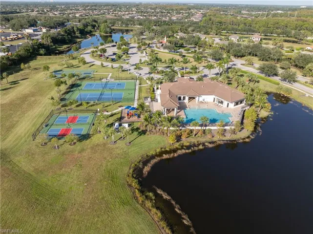 Aerial view of residential area featuring a nearby body of water and a pool area
