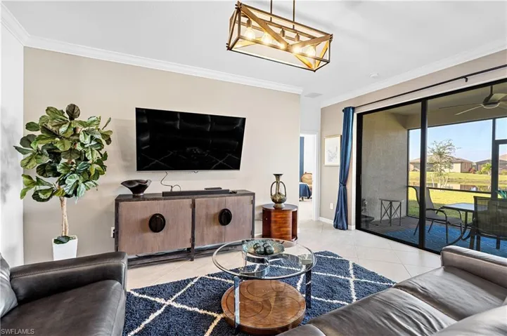 Living area featuring ornamental molding, light tile patterned floors, and ceiling fan
