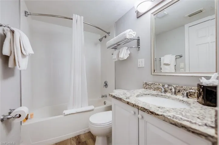Full bathroom with shower / tub combo with curtain, wood-type flooring, toilet, and vanity