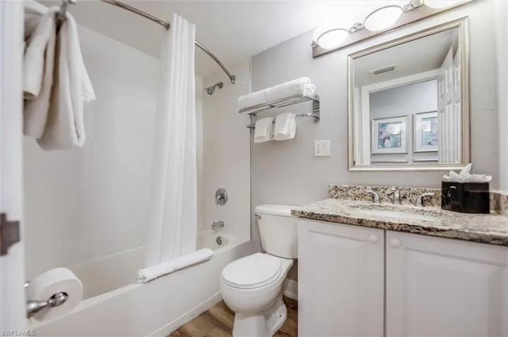 Full bathroom with vanity, hardwood / wood-style floors, toilet, and shower / bath combo with shower curtain