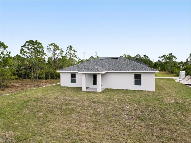 Back of house with stucco siding, a yard, and a patio