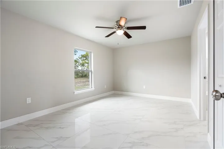 Spare room featuring light marble finish floors and a ceiling fan