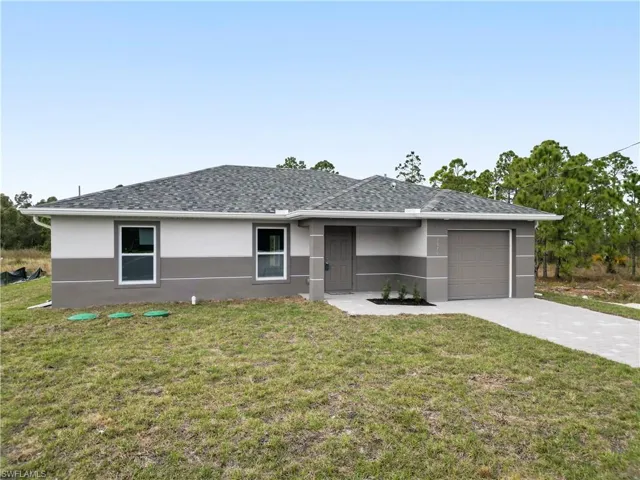 Ranch-style house featuring stucco siding, a front lawn, driveway, and a garage