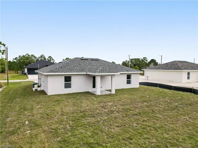 Back of property with stucco siding, a patio, and roof with shingles