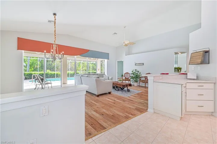 Kitchen with a notable chandelier, decorative light fixtures, lofted ceiling, white cabinets, and light hardwood / wood-style floors
