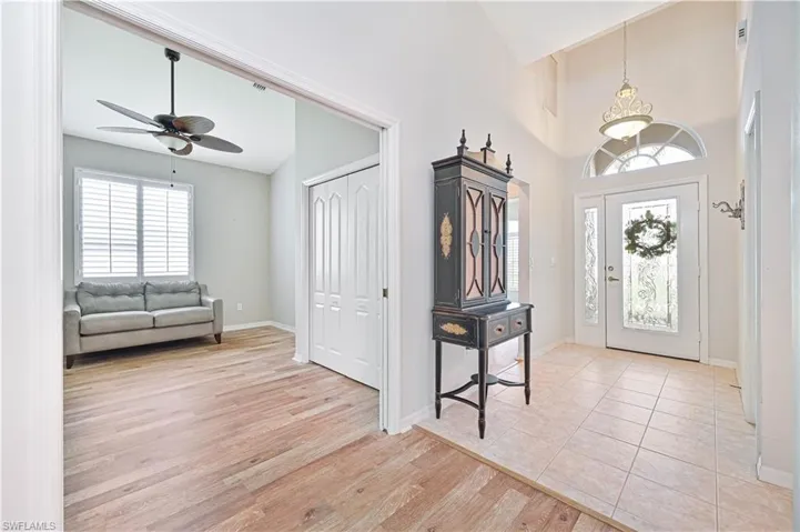Foyer entrance with light hardwood / wood-style flooring, ceiling fan with notable chandelier, and high vaulted ceiling