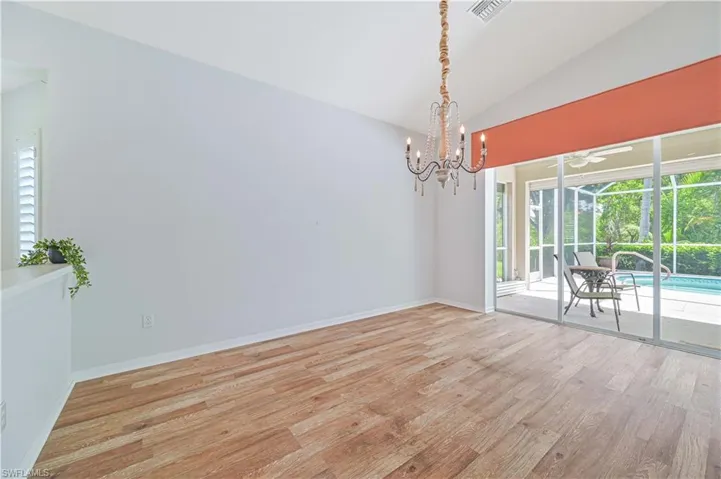 Unfurnished room with lofted ceiling, wood-type flooring, and an inviting chandelier