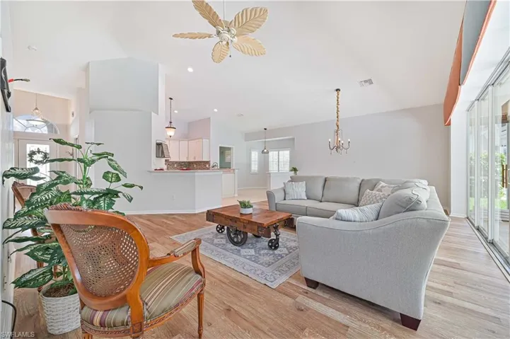 Living room featuring lofted ceiling, a wealth of natural light, a chandelier, and light hardwood / wood-style flooring