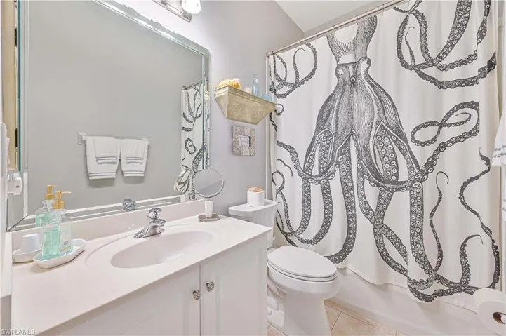 Full bathroom with tile flooring, shower / bath combination with curtain, vanity, and toilet